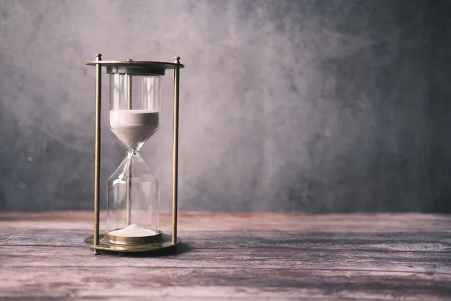 An hourglass with sand running through it on a rustic wooden table