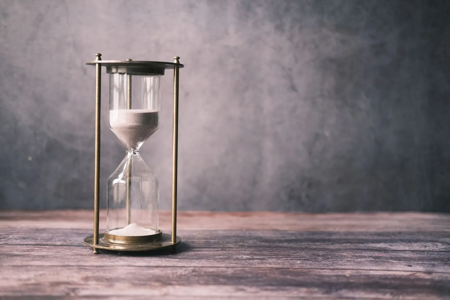 An hourglass with sand running through it on a rustic wooden table